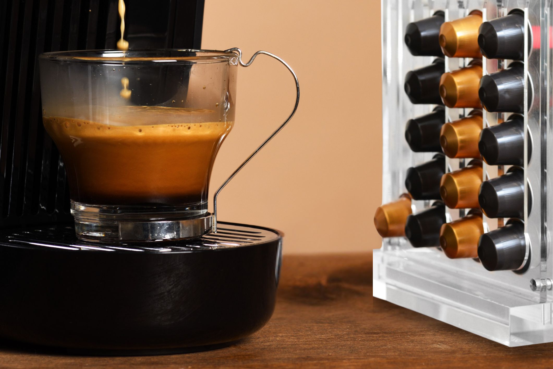 Comparação entre cápsulas de café originais e compatíveis colocadas ao lado de uma máquina de café de cápsulas doméstica.